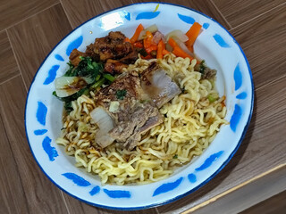 Guring beef noodle soup, equipped with delicious toppings, served on a traditional Indonesian iron plate.