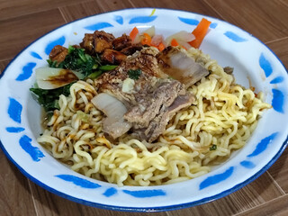 Guring beef noodle soup, equipped with delicious toppings, served on a traditional Indonesian iron plate.