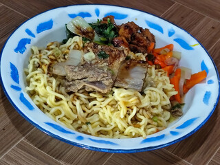 Guring beef noodle soup, equipped with delicious toppings, served on a traditional Indonesian iron plate.