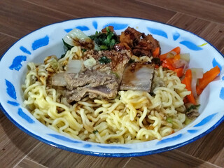Guring beef noodle soup, equipped with delicious toppings, served on a traditional Indonesian iron plate.
