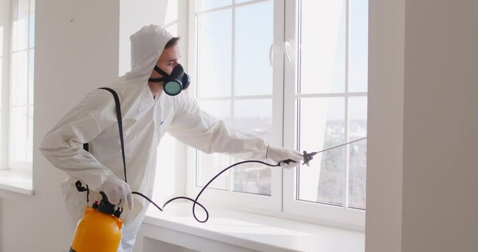Man pest control worker spraying insecticide around house, eliminating bugs, taking care of free clean home environment, wearing protective workwear, spraying pesticide. Pest control service