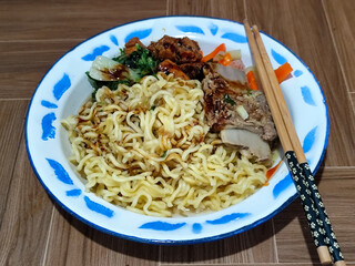 Guring beef noodle soup, equipped with delicious toppings, served on a traditional Indonesian iron plate.