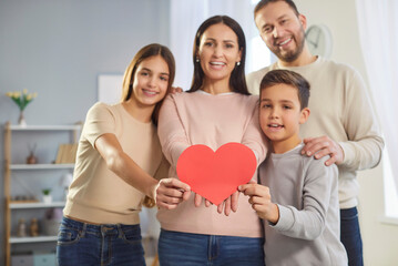 Happy mother father and two children posing together showing big heart postcard celebrating...