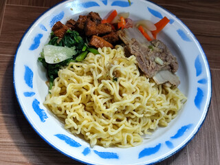 Guring beef noodle soup, equipped with delicious toppings, served on a traditional Indonesian iron plate.