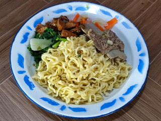 Guring beef noodle soup, equipped with delicious toppings, served on a traditional Indonesian iron plate.