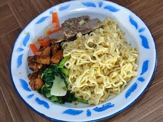 Guring beef noodle soup, equipped with delicious toppings, served on a traditional Indonesian iron plate.