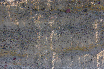 Weathered Cheap Uneven Concrete Surface with Pebbles under tangential harsh light