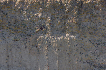 Weathered Cheap Uneven Concrete Surface with Pebbles under tangential harsh light