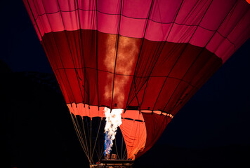 Hot air balloon filling with air using gas burner in dawn light