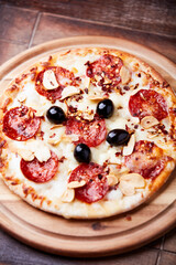 Pizza with salami and mozzarella cheese. Wooden background. Soft focus. Close up.	
