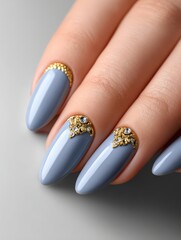 Elegant manicure featuring a stylish blue polish with gold and jewel accents for modern nail art inspiration.