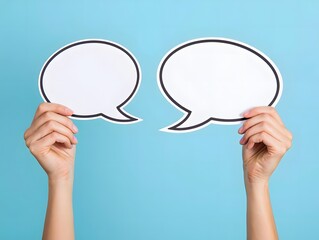 Hands Holding Up Two Blank White Speech Bubbles Promoting Communication and Conversation on a Light Blue Background Studio Shot for Social Media Content
