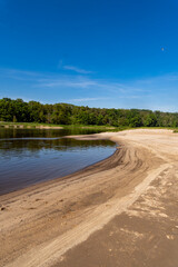 Peaceful sandy riverbank with clear blue sky