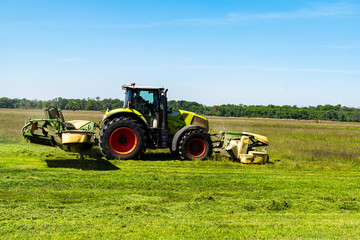 Side view of tractor with mower cutting grass on summer field