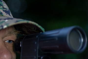 A man in a pixel camouflage cap takes aim with a shotgun. The theme is hunter, soldier or sniper in...