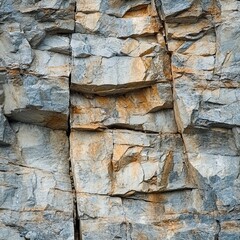 Fototapeta premium Rocky texture background: A detailed close-up shot reveals the rugged texture and intricate patterns of a rock face, showcasing a mix of grey and orange hues.