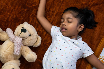 Child sleeping peacefully beside a teddy bear