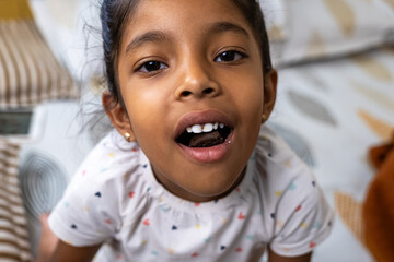 Smiling girl showing off her new teeth on a cozy bed