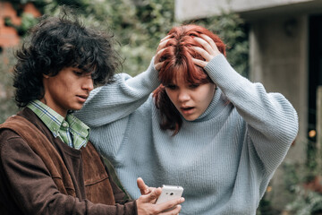 Angry teenage couple arguing while looking at their cell phones on the street