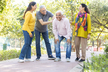 Obraz premium Group of happy indian senior men and women laughing and walking together in summer park. Retirement life, retired people enjoying in garden