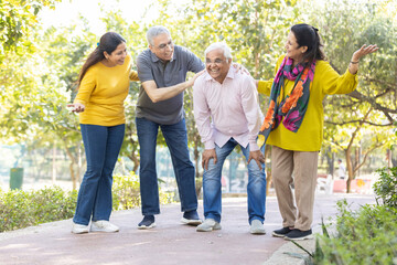 Group of happy indian senior men and women laughing and walking together in summer park. Retirement life, retired people enjoying in garden
