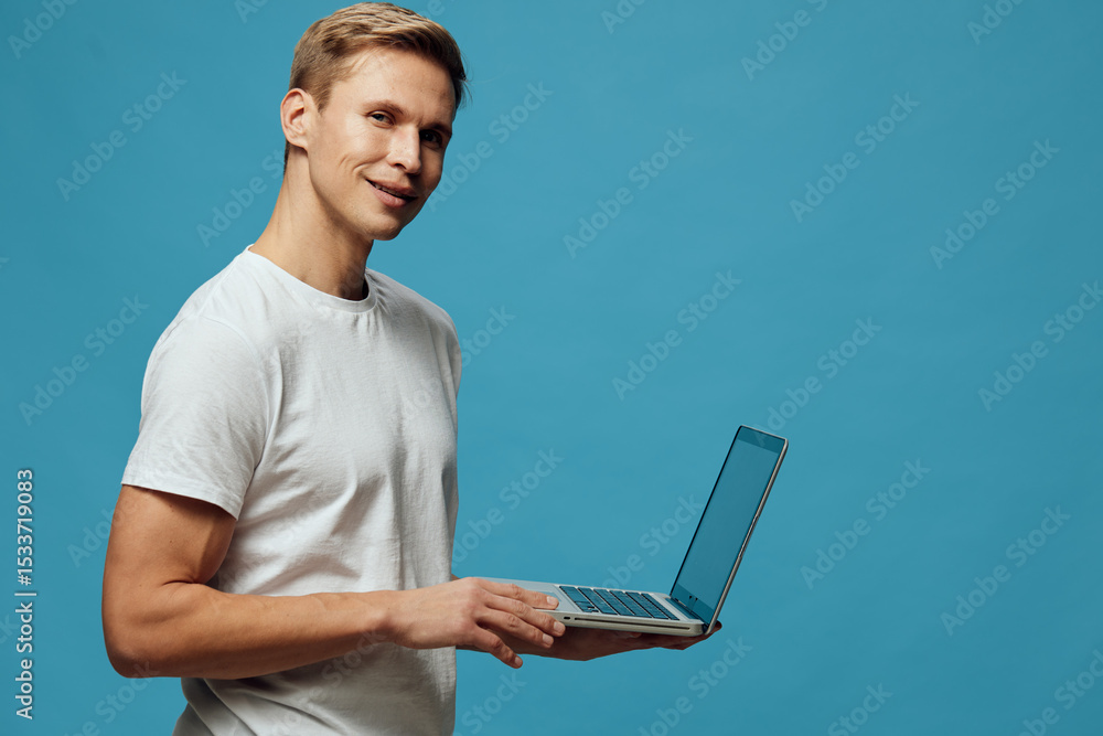 Aufkleber man holding laptop computer with open screen in hand, smiling at camera, dressed casually in light t