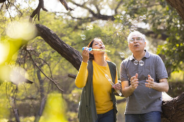Senior couple blowing bubbles at park