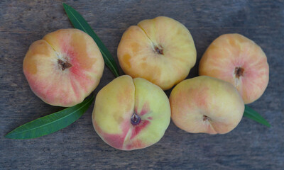 A bunch of flat peaches on a board