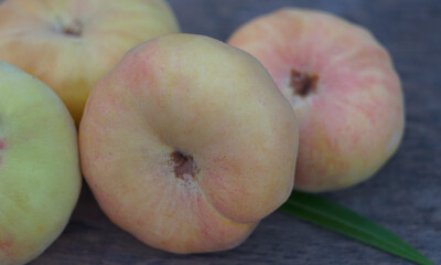 A bunch of flat peaches on a board