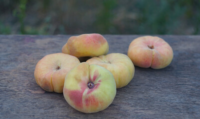 A bunch of flat peaches on a board