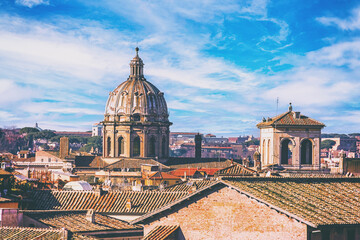 Scenic view of Rome rooftops with dome of baroque church and historic architecture under bright blue sky. Rome, Italy