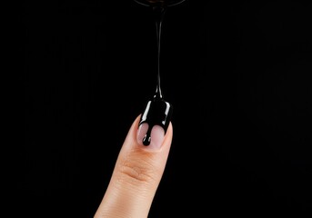 Black liquid dripping onto a finger with a black background in a studio setting close up shot