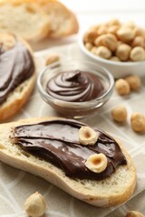 Slices of bread with chocolate spread and hazelnuts on table, closeup