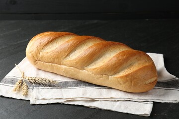 Loaf of bread and spikes on black textured table, closeup