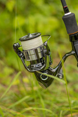 Fishing reel close-up. spinning rod and reel against the background of grass. High quality photo