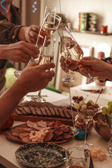 Friends and relatives clinking glasses of champagne at the table to celebrate the holidays
