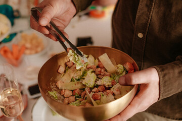 Male hands holding golden bowl with fresh Caesar salad