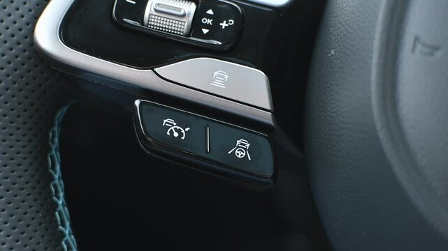 Close-up of modern car steering wheel with adaptive cruise control and lane keeping assist buttons, illustrating advanced vehicle technology.