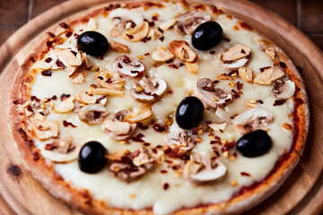 Pizza with champignons, black olives and mozzarella cheese. Wooden background. Soft focus.	
