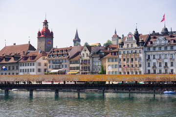 Cityscape with old town of Swiss city of Luzern with River Reuss and medieval covered wooden footbridge Chapel Bridge on a sunny late spring day. Photo taken June 12th, 2025, Lucerne, Switzerland.