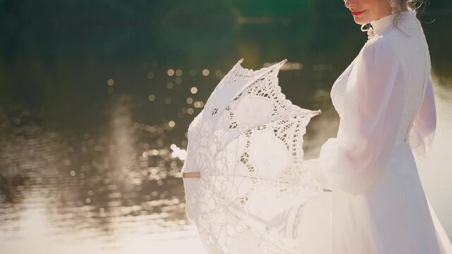 happy woman spinning white lace umbrella in hands, cropped face close-up lips, girl regency era old style, white vintage victorian dress. lady stands by river bank green trees fairy nature sun light