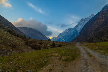 Majestic mountain range with dirt road in serene valley at springtime evening