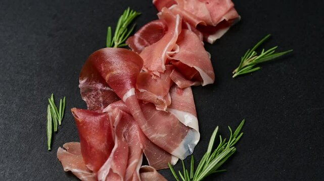 Explore the exquisite tastes of prosciutto crudo di Parma and Spanish jamon as they are elegantly displayed with fresh herbs, enhancing any charcuterie experience