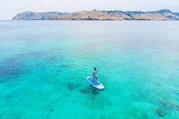 Paddle boarder in turquoise tropical water, man enjoying summer vacation, perfect for travel