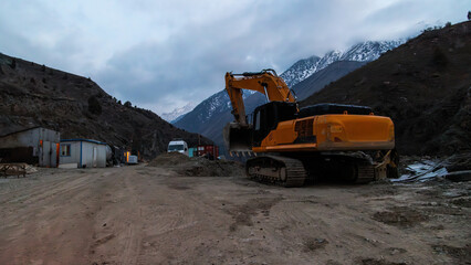 Excavator at construction site in mountainous region during late evening