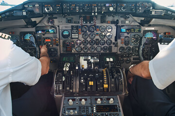 Pilots operating aircraft controls inside cockpit during flight