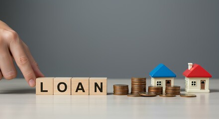 A hand arranges wooden blocks spelling "LOAN" with coin stacks and model houses in the background.