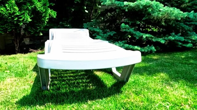 Closeup white plastic deck chair in the garden. Concept of leisure and recreation