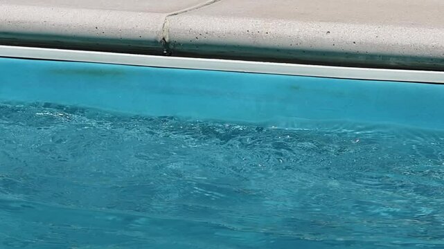 Closeup water waves against the wall of a swimming pool on a bright summer day