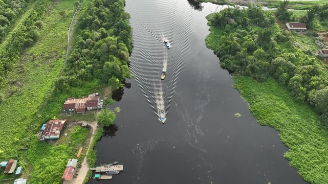Time laps of Drone view of Lush green scenery lining the winding river with boats plying the calm waters, offering enchanting natural scenery and activities along its banks in Sumatera